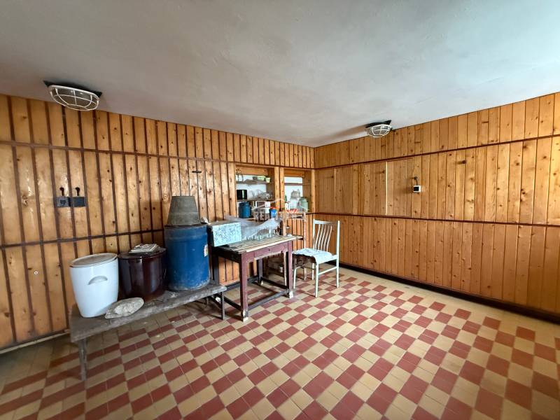 Interior with wooden walls, tiles, a chair, and a table in a family house.