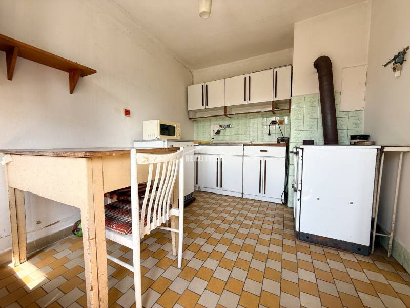 A kitchen in a family house with retro equipment, ceramic tiles, and old furniture.