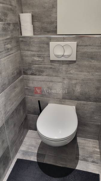 WC with tiles in a 1-room apartment, gray tiles and a toilet paper holder.