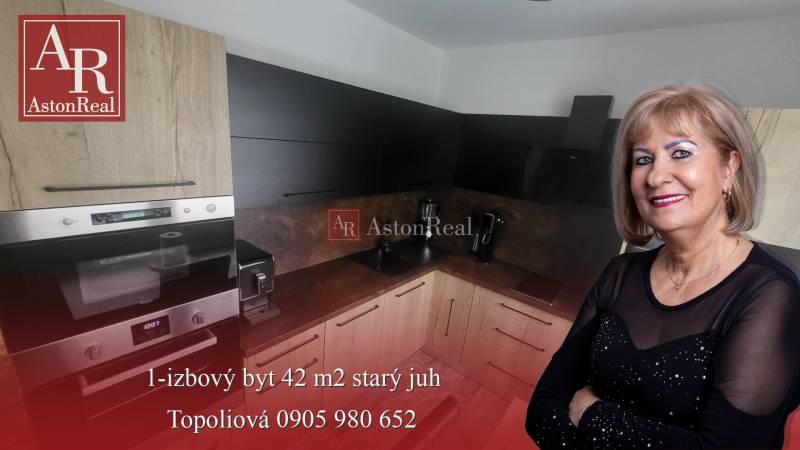 A kitchen in a studio apartment with wooden cabinets and modern appliances.