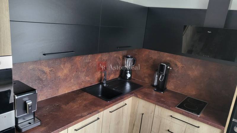 A kitchen in a studio apartment with modern appliances and black cabinets.