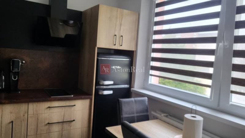 A kitchen in a studio apartment with a cooktop, coffee maker, and refrigerator.