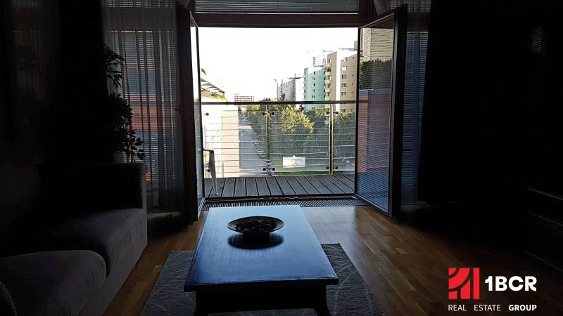 Living room of a two-room apartment with a view of the balcony and city skyline.