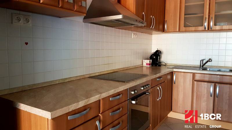A kitchen in a 2-room apartment with wooden cabinets, a cooktop, and a sink.