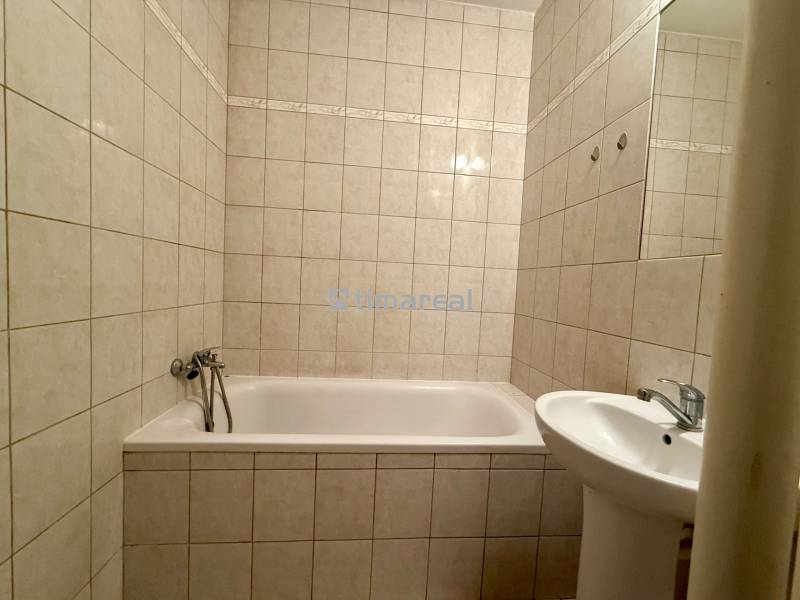 A bathroom with a bathtub and a sink in a 2-room apartment with ceramic tiles.
