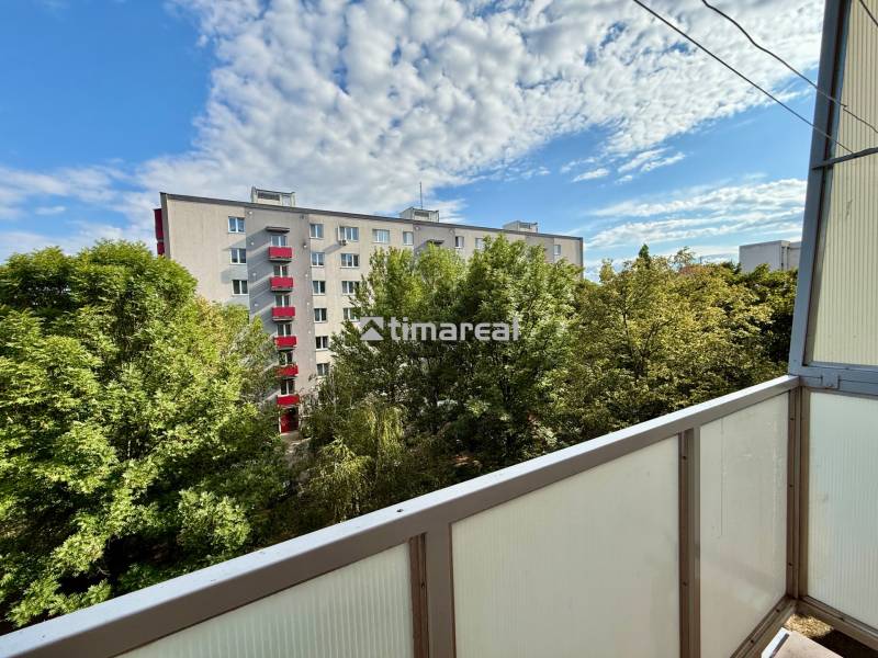 A view from the balcony surrounded by trees and a view of the apartment building on Špačinská Street in Trnava.
