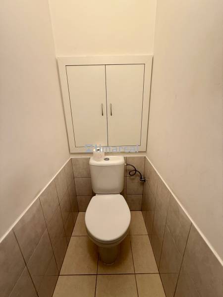 A toilet with a cabinet in a 2-room apartment, white tiles and floor tiles.