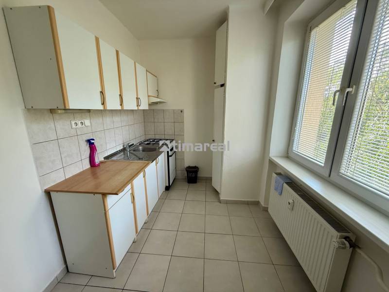 A kitchen with white cabinets and a window in a 2-room apartment.