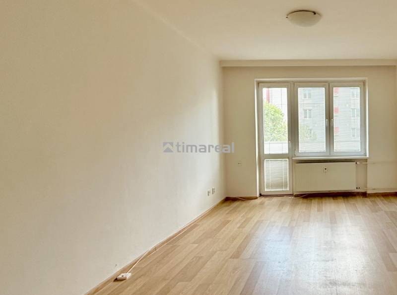 A room with a wooden floor and windows in a 2-room apartment, light penetrates inside.