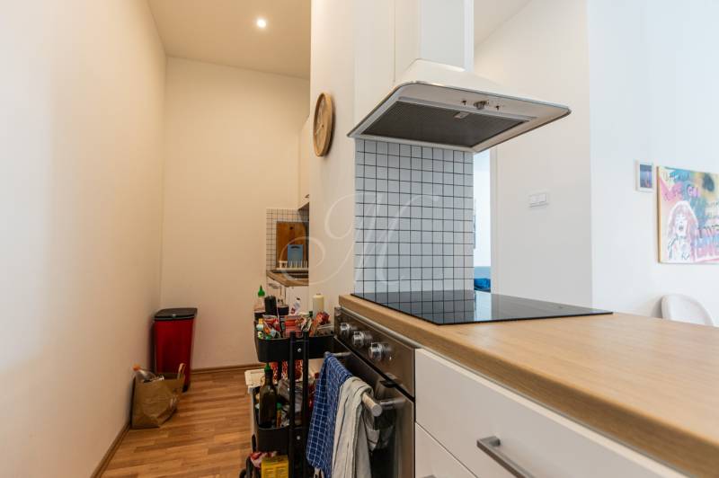 A kitchen in a 2-room apartment with an oven, a hood, and a wooden floor.