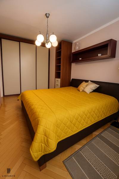 Bedroom in a 2-room apartment with a double bed, wardrobe, and hanging light fixture.