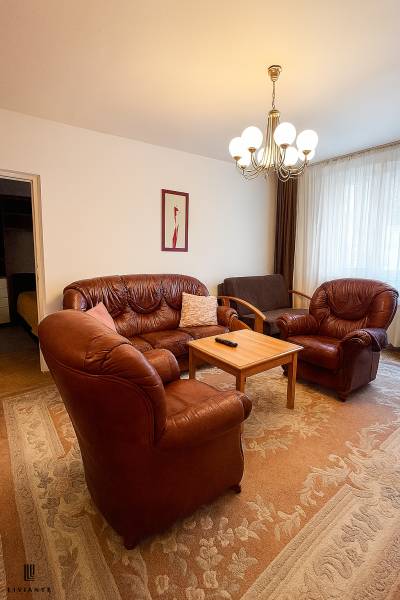 Leather sofa set in the living room of a 2-room apartment with a chandelier and a carpet.