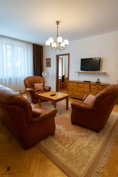 Living room in a two-room apartment with a leather sofa set and wooden furniture.