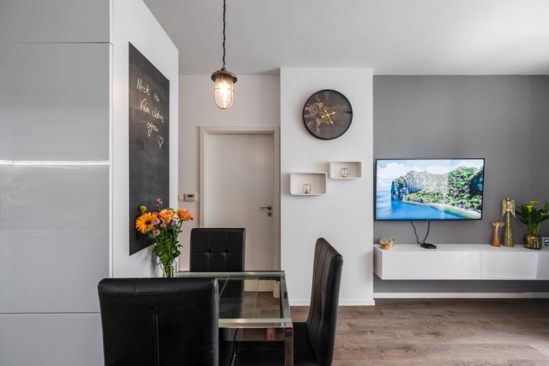 A stylish living room in a two-room apartment with a television, an armchair, and flowers on the table.