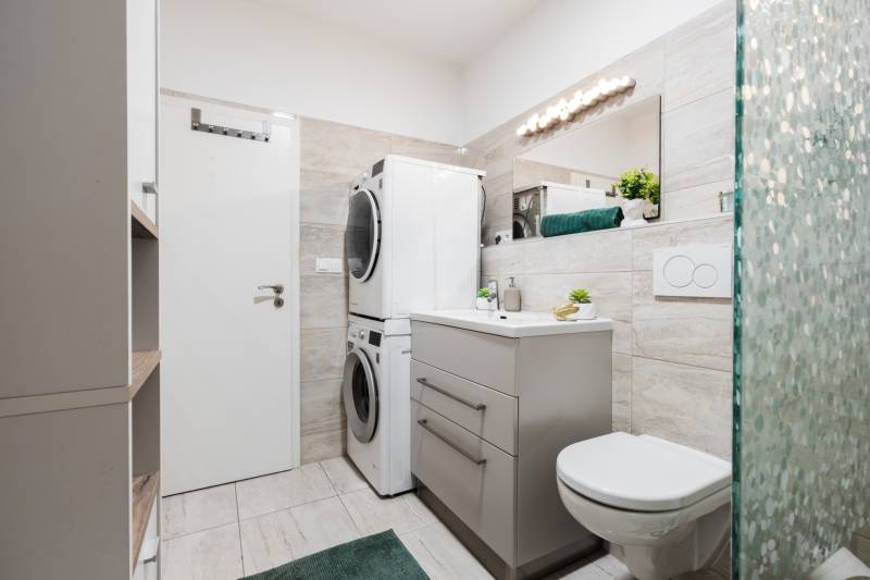Bathroom with a washing machine and dryer in a 2-room apartment, modern tiles and sanitary ware.