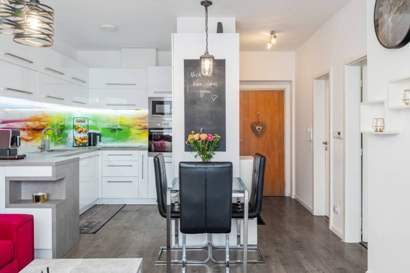 A kitchen in a 2-room apartment with a dining table and colorful tiles.