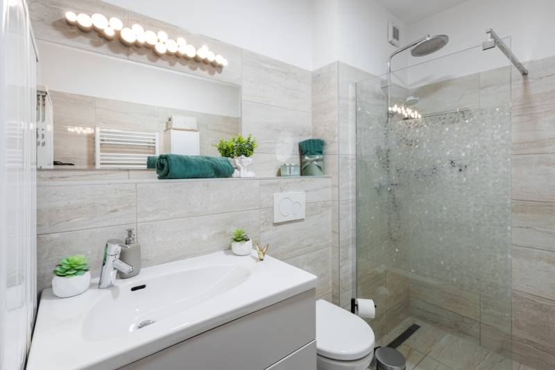 Bathroom in a 2-room apartment with a shower and a sink, furnished in soft colors.