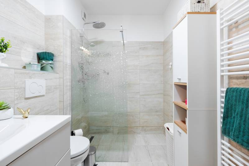 Bathroom in a 2-room apartment with a shower, towel, and ceramic tiles.