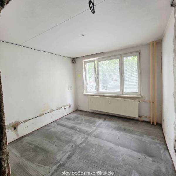 A room under renovation with an empty floor and a large window in a 2-room apartment.