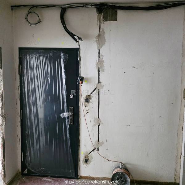 Renovation in a 2-room apartment, doors secured with protective film, visible cable installations.