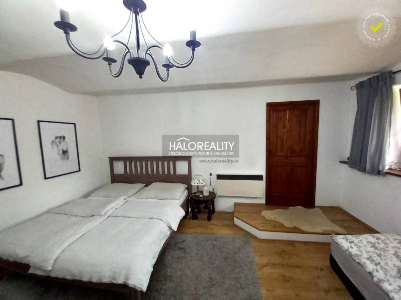 A bedroom with a wooden bed, chandelier, and paintings in a family house.