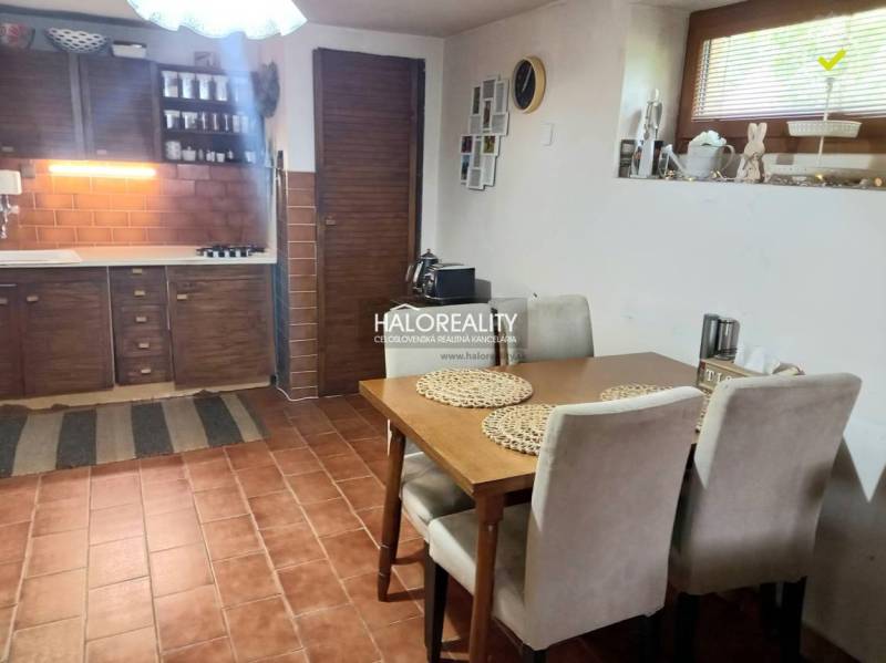 A kitchen in a family house with wooden furniture, brick cladding, and a dining table.