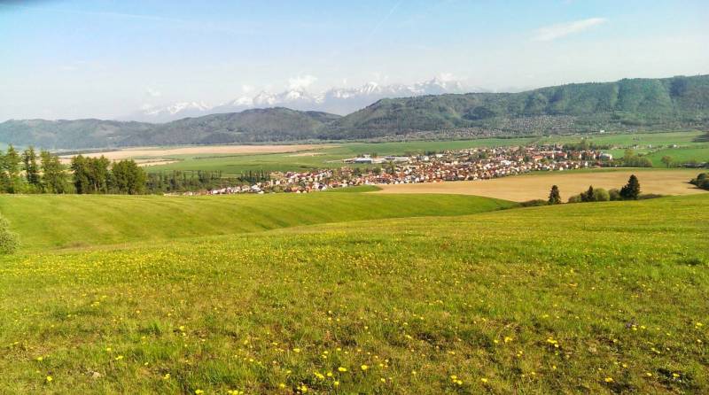 View of agricultural and forest land near Hranovnica with mountains in the background.