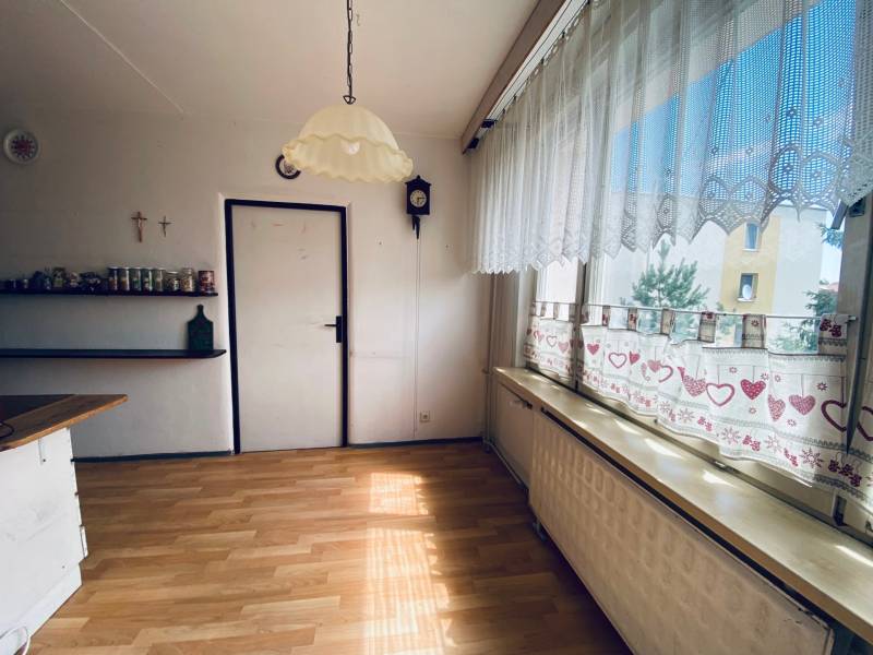 A room with curtains, a view, wooden floor, and a shelf in a 4-room apartment.