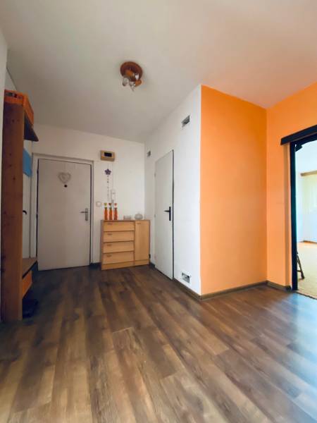 A hallway in a 4-room apartment with wooden flooring and orange-white walls.