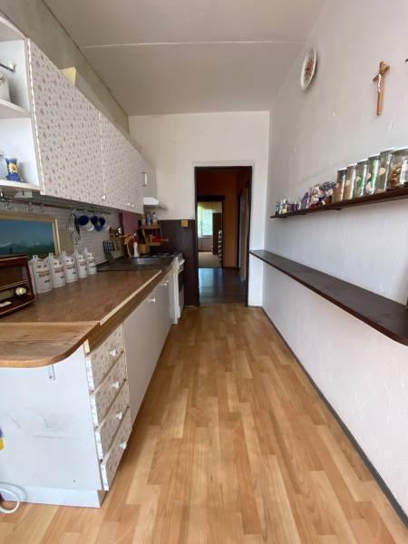 A kitchen in a 4-room apartment with patterned cabinets and a shelf with glasses.