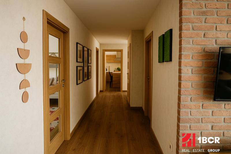 A hallway in a family house with wooden flooring, decorations on the walls, and a view into the kitchen.