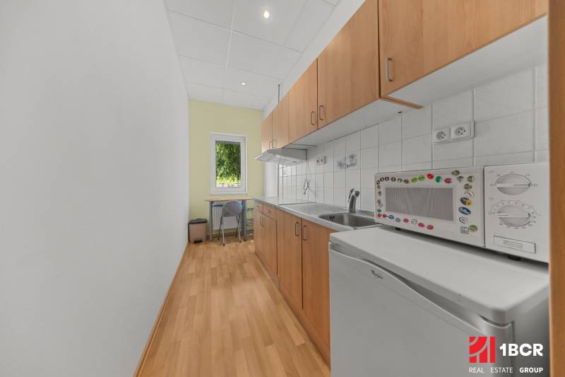 A family house kitchen with a microwave, refrigerator, and wooden cabinets, designed for practical use.