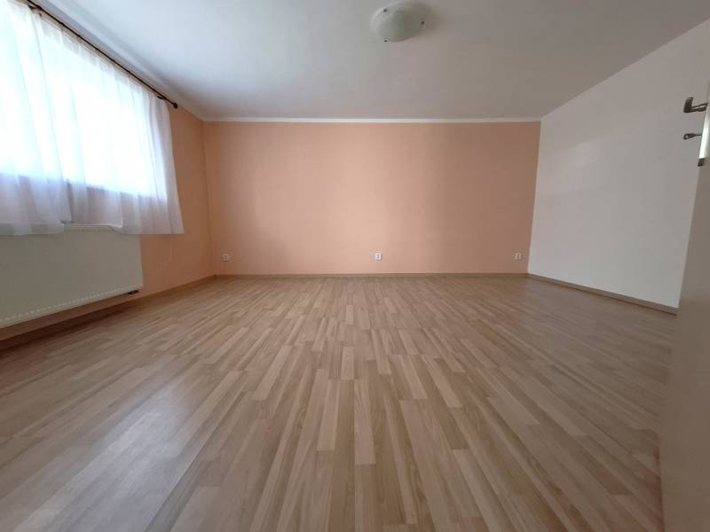 A spacious room with wooden flooring and an orange wall in a 4-room apartment.