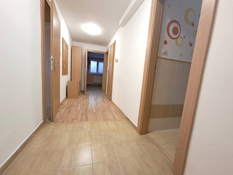 A hallway in a 4-room apartment with wooden doors and tiled flooring.
