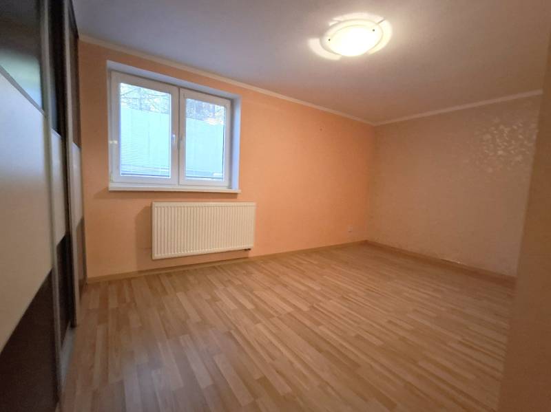 A room in a 4-room apartment with laminate flooring, orange walls, and a window with blinds.