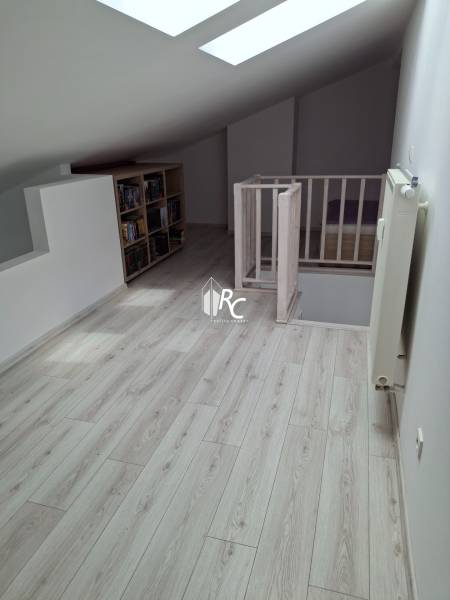 Attic room with stairs, wooden floor, and a bookshelf.