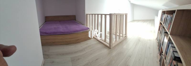 Attic room in a 4-room apartment with a bed, a bookshelf, and stairs.