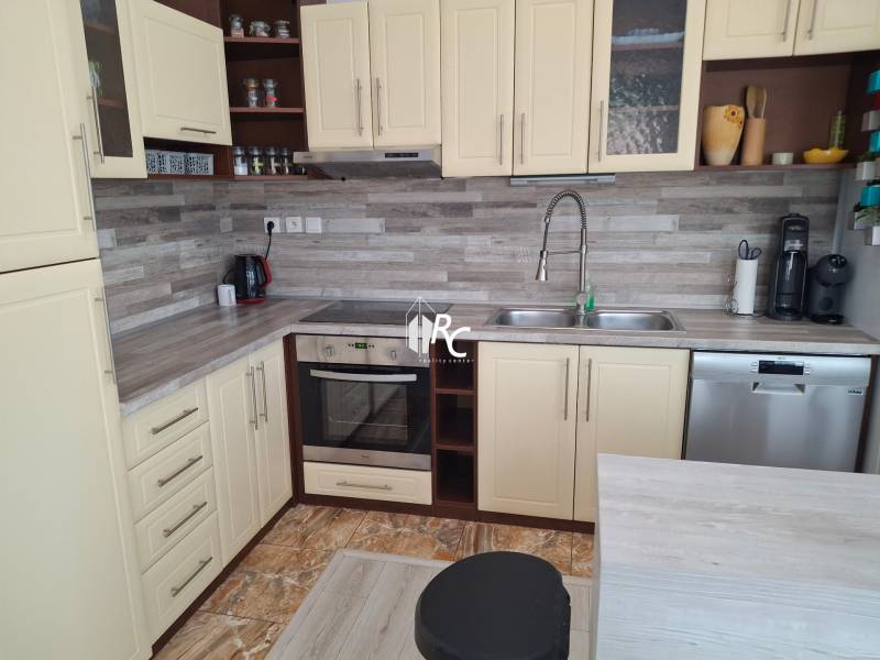 A kitchen in a 4-room apartment with cream cabinets and stainless steel appliances.