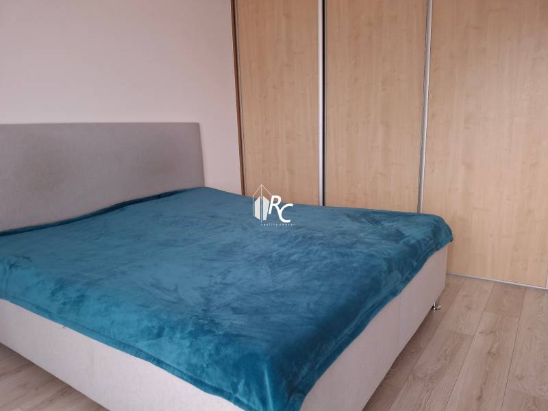 Bedroom in a 4-room apartment with a gray bed and a blue throw.