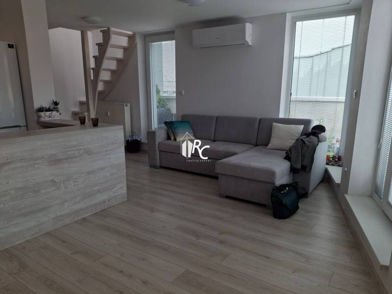 Living room with a sofa, stairs, and wooden floor in a 4-room apartment.