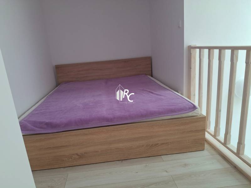 Simple bedroom with a wooden bed and a purple blanket in a 4-room apartment.