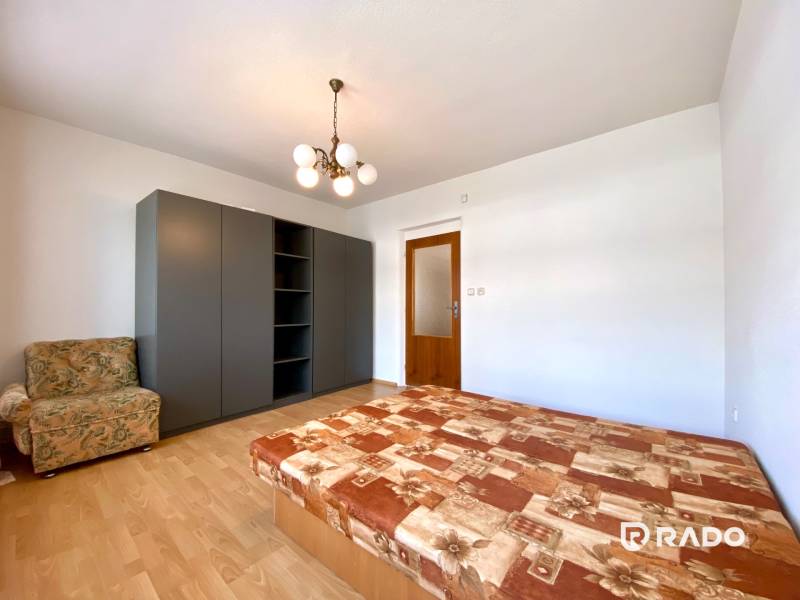 Bedroom in a 2-room apartment with a bed, wardrobe, and armchair.