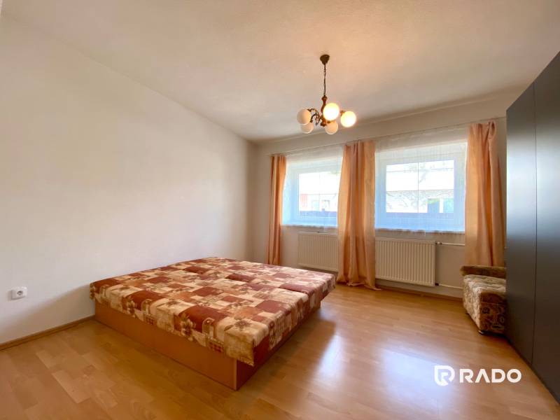 A bedroom with a ceiling light in a two-room apartment with two windows and a bed.