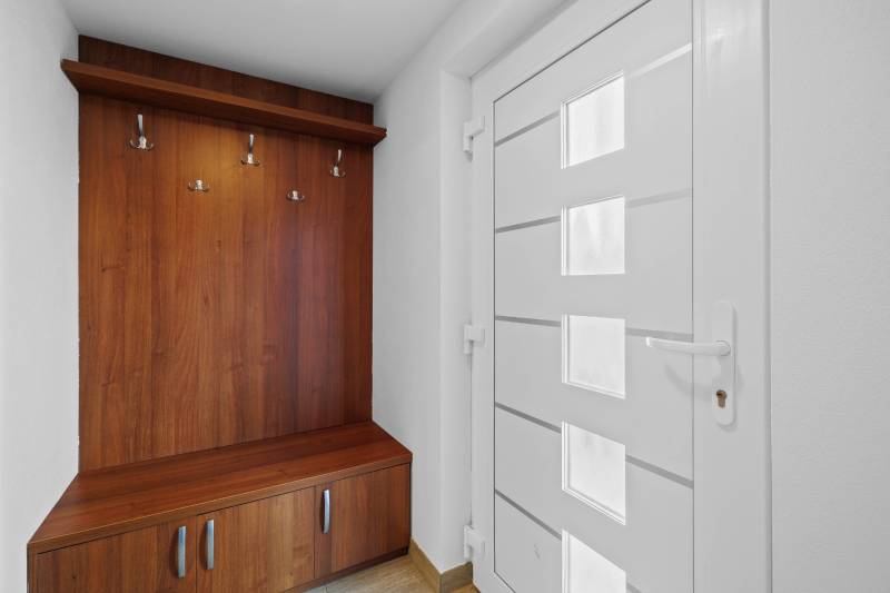 The hallway of a family house, a wooden coat rack, and white doors on Pluhová Street.