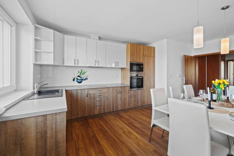 Kitchen and dining room with light cabinets and wooden floors, on Pluhová street.