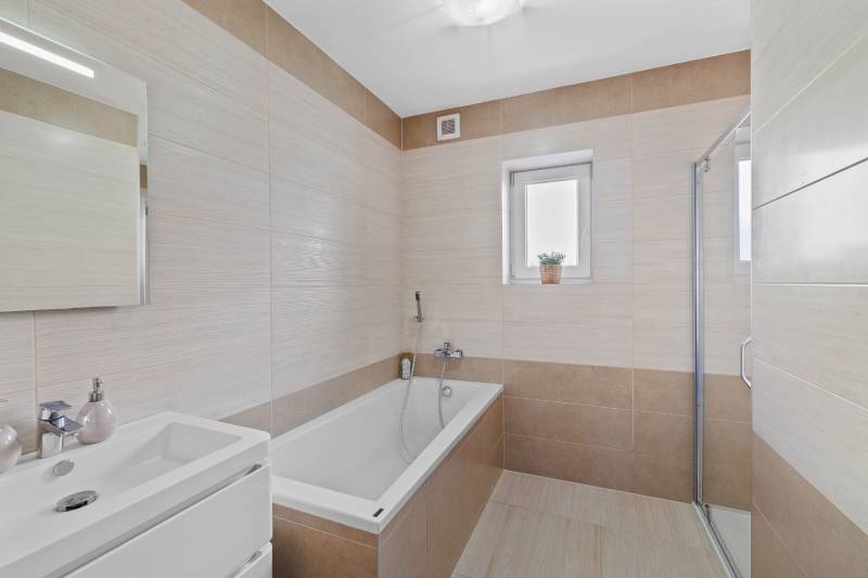 Bathroom in a family house on Pluhová street, with a bathtub and a shower.