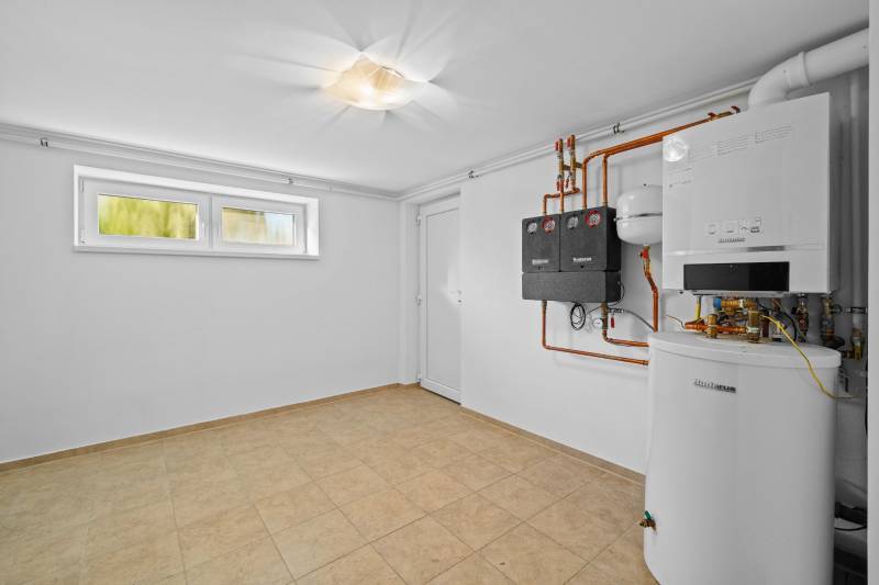 Heating, white walls, and a window with a heat pump on Pluhová Street in a family house.