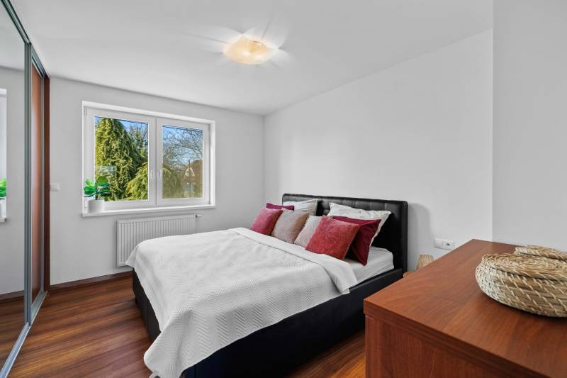 Bedroom in a family house on Pluhova Street with a bed and wooden floors.