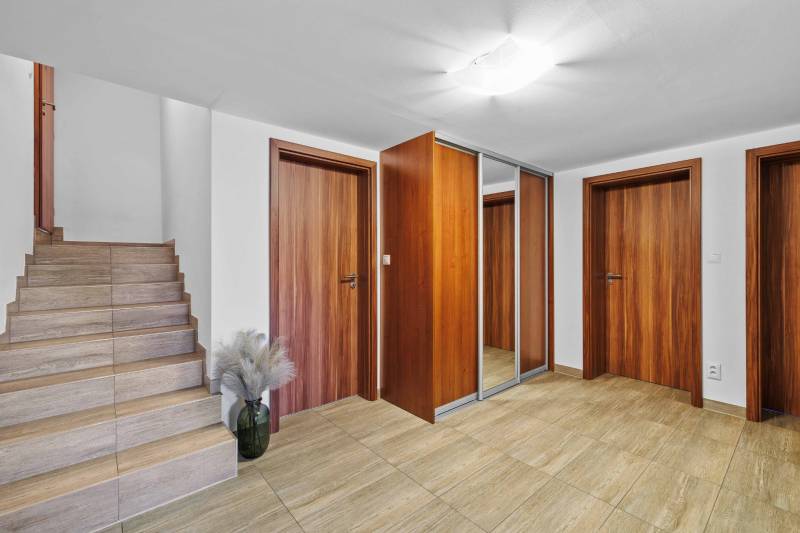 Entrance hall in a family house with wooden doors and a staircase on Pluhová Street.