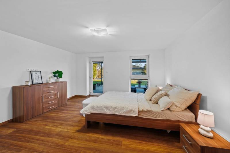 Bright bedroom in a family house with wooden flooring and a view of Pluhová Street.